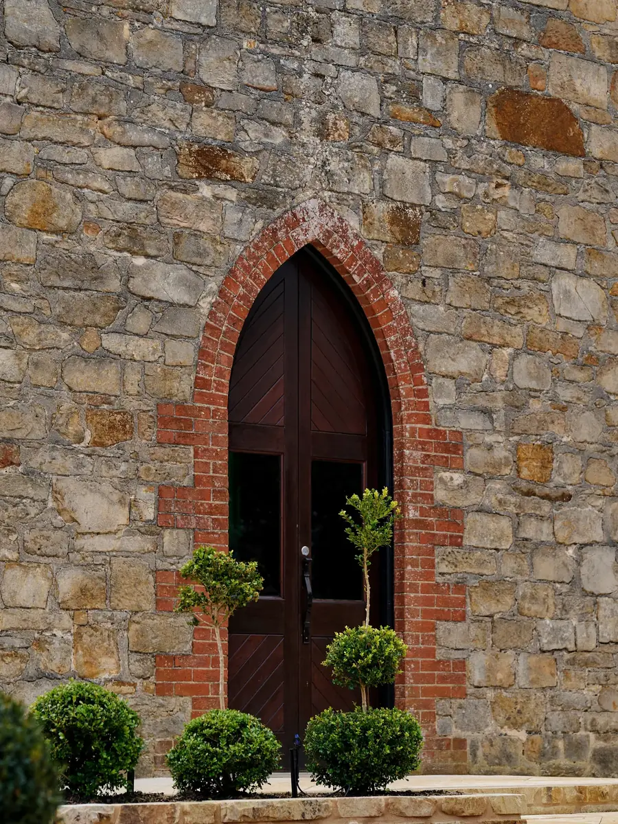 The arched timber door in the 1892 stone wall