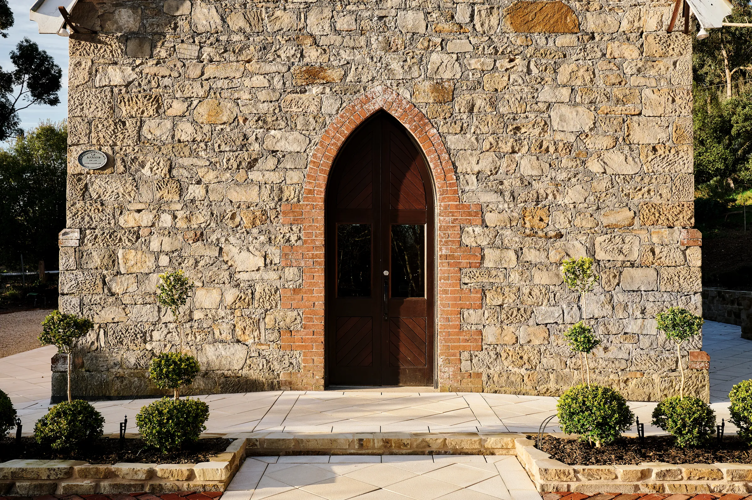 The stone front elevation and arched timber door of St. Stephen’s Uraidla