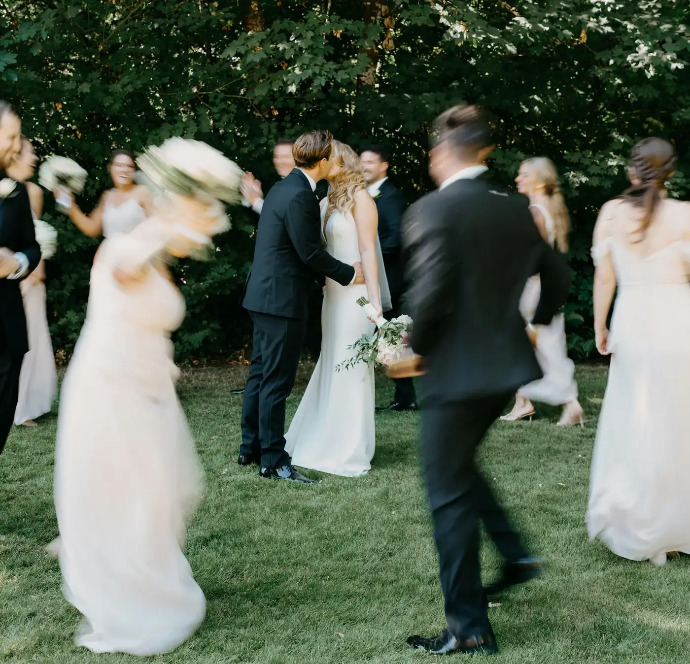 A wedding party moving around a couple on the lawn at St. Stephen’s